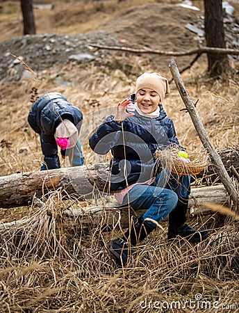 Cute girls having Easter egg hunt at forest at cold april day Stock Photo