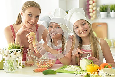 Cute girls with mother preparing delicious fresh salad in kitchen Stock Photo