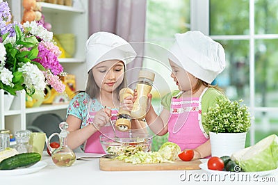 Cute girls preparing delicious fresh salad in kitchen Stock Photo