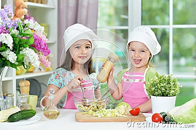 Cute girls preparing delicious fresh salad in kitchen Stock Photo