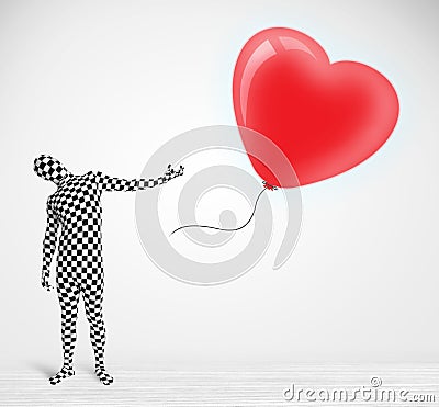 Cute guy in morpsuit body suit looking at a balloon shaped heart Stock Photo