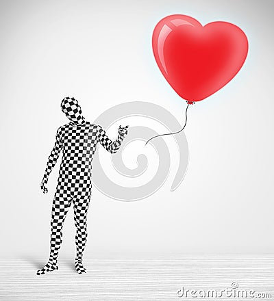 Cute guy in morpsuit body suit looking at a balloon shaped heart Stock Photo