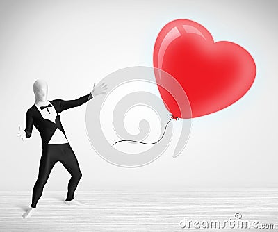 Cute guy in morpsuit body suit looking at a balloon shaped heart Stock Photo