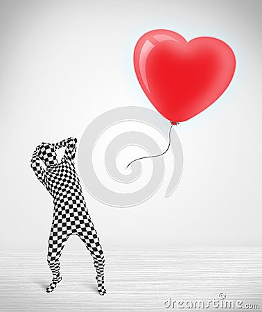 Cute guy in morpsuit body suit looking at a balloon shaped heart Stock Photo