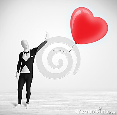 Cute guy in morpsuit body suit looking at a balloon shaped heart Stock Photo