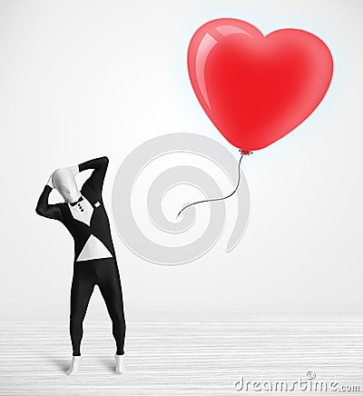 Cute guy in morpsuit body suit looking at a balloon shaped heart Stock Photo