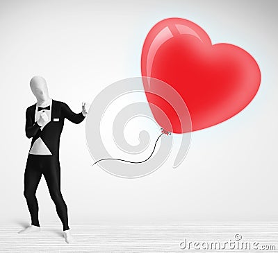 Cute guy in morpsuit body suit looking at a balloon shaped heart Stock Photo