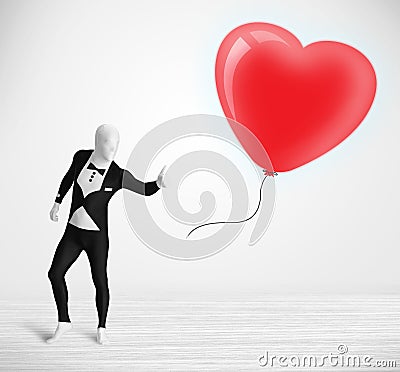 Cute guy in morpsuit body suit looking at a balloon shaped heart Stock Photo