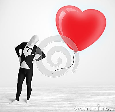 Cute guy in morpsuit body suit looking at a balloon shaped heart Stock Photo