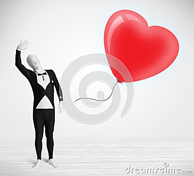 Cute guy in morpsuit body suit looking at a balloon shaped heart Stock Photo