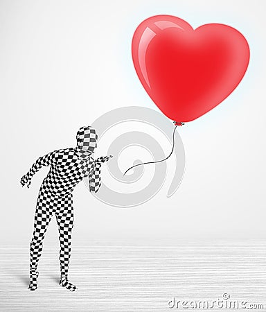 Cute guy in morpsuit body suit looking at a balloon shaped heart Stock Photo