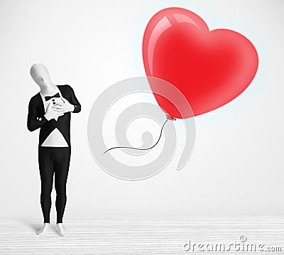 Cute guy in morpsuit body suit looking at a balloon shaped heart Stock Photo