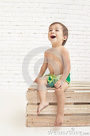 Cute handsome toddler laughing while sitting on wooden box Stock Photo