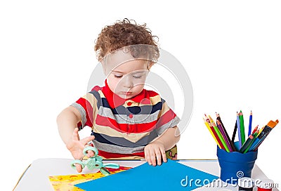 Cute happy baby boy cutting colorful paper Stock Photo