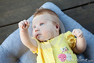 Cute happy one month baby girl in yellow clothing lying and playing Stock Photo