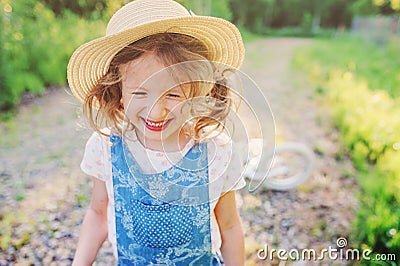 Cute happy child girl with bicycle on summer sunny road Stock Photo