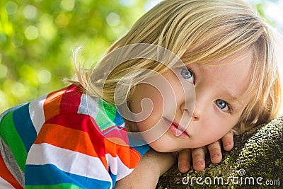 Cute, happy child relaxing deep in thought outdoors Stock Photo