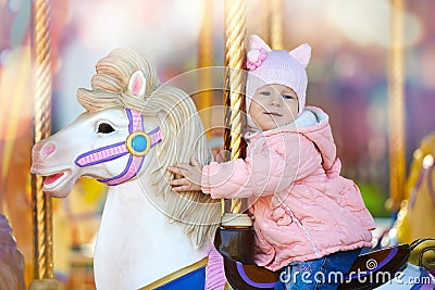 Cute happy child riding the horse on the colorful merry go round Stock Photo