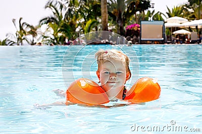 Cute happy little toddler girl swimming in the pool and having fun on family vacations in a hotel resort. Healthy child Stock Photo