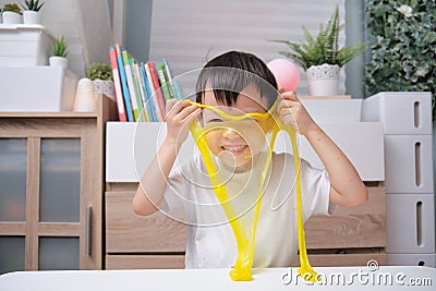 Asian Kindergarten school boy having fun making yellow fluffy slime, Young kid having fun playing and being creative by science Stock Photo