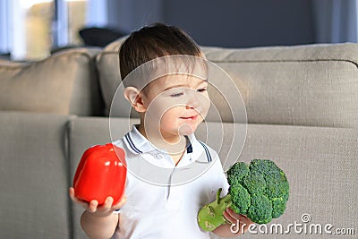 Cute happy smiling little boy holding raw vegetables broccoli and red pepper in his hands. Healthy food, diet, vegetarianism and v Stock Photo
