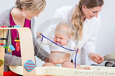 Cute and healthy baby girl playing with the stethoscope during routine check-up Stock Photo