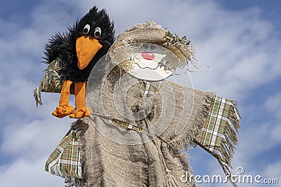 Cute humanoid scarecrow together with a crow on a background of blue sky, Ukraine. Close up Stock Photo