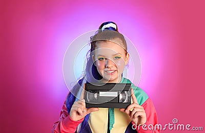 Cute indie girl with VHS cassette on violet background Stock Photo