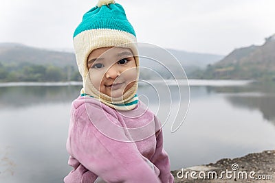 cute infant in winter dress and monkey cap innocent facial expression at morning Stock Photo