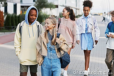 Cute intercultural school learners with backpacks chatting on their way home Stock Photo