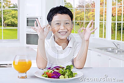 Cute kid with fresh salad shows OK sign Stock Photo