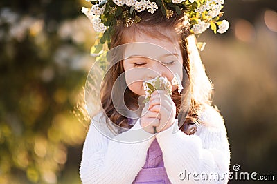 Cute kid girl 2-3 year old smell flowers over green nature background close up. Spring season. Childhood Stock Photo