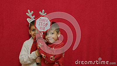 Cute kids brothers hugging and showing santa stop here sign. Christmas celebration and happy family. Stock Photo