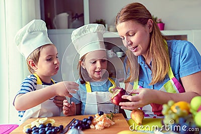 Cute kids with mother preparing a healthy fruit snack in kitchen Stock Photo