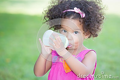 Cute latin girl drinking from a baby bottle Stock Photo