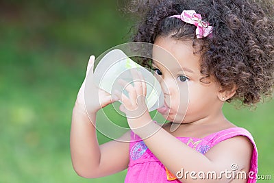 Cute latin girl drinking from a baby bottle Stock Photo