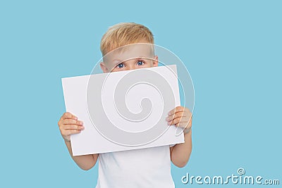 A cute laughing child boy is holding a white signboard with an empty space for text. Advertising Stock Photo