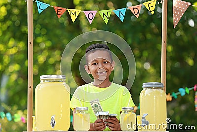 Cute little African-American boy with money at lemonade stand. Summer refreshing natural drink Stock Photo