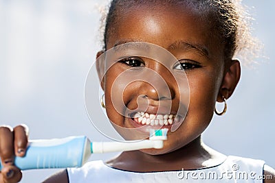 Cute little afro girl holding electric toothbrush. Stock Photo