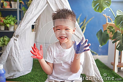 Cute little Asian boy child finger painting with hands and watercolors at home, Creative play for kids and toddlers concept Stock Photo