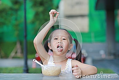 Cute little Asian child girl eating Instant noodles on the table Stock Photo