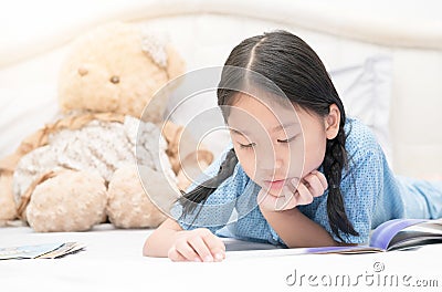 Cute little asian girl reading fairy tales on bed Stock Photo