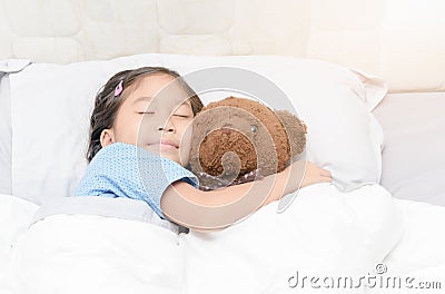 Cute little asian girl sleep and hug teddy bear on bed Stock Photo