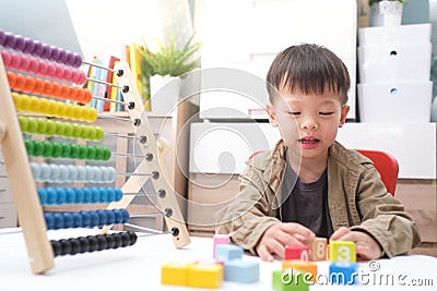 Cute little asian using the abacus with beads and wooden brick with numbers to learn how to count at home, Use an Abacus to teach Stock Photo