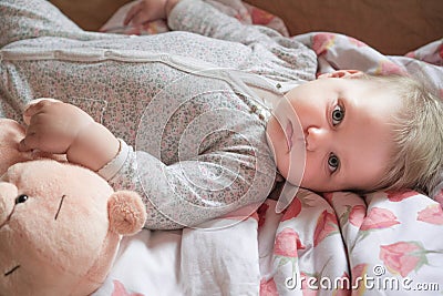 A cute little baby is woke up and lies on the bed, calm and pacified Stock Photo