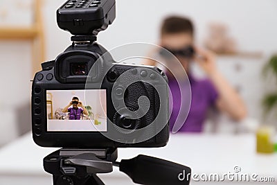 Cute little blogger with binoculars recording video at home Stock Photo