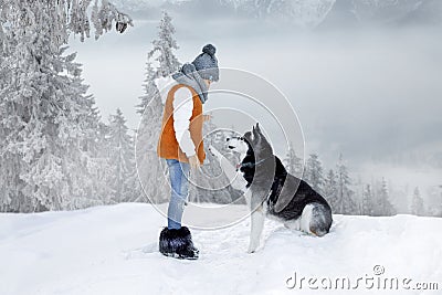 Cute little blonde girl playing in the snow with a dog Husky Stock Photo