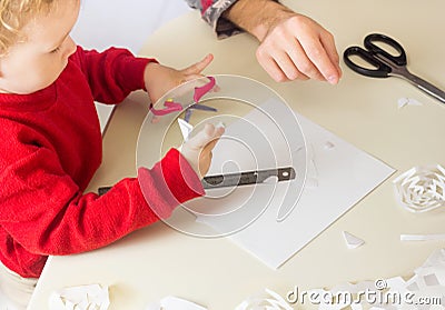 Cute little Boy cuts out snowflakes for Christmas decoration. New Year Decor. Festive craft and seasonal activity Stock Photo