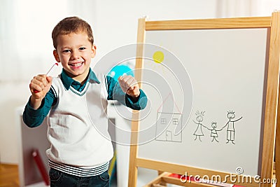 Cute little boy drawing on white board with felt pen and smiling Stock Photo