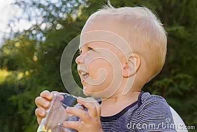 Cute little boy drinkng a glass of fresh water. Funny laughing toddler Stock Photo